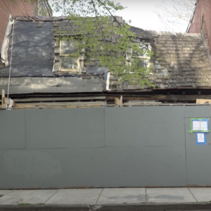 Caulkers' houses in Baltimore, MD. Small rowhouses in undergoing restoration. Only roof visible behind construction fence.